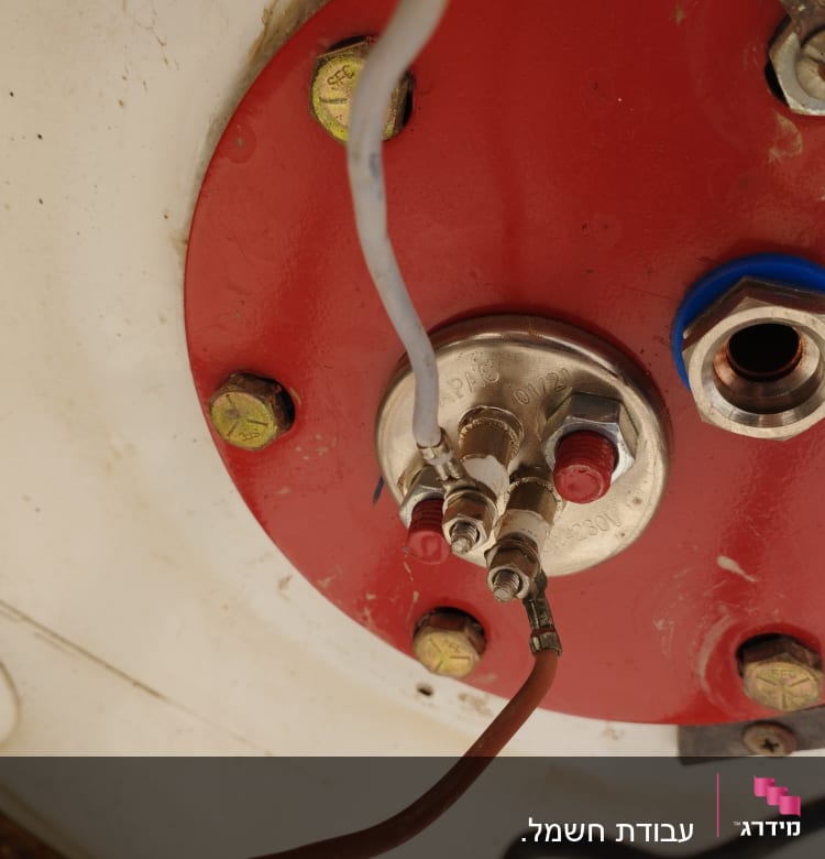 חיבורים חשמליים על לוח מתכת אדום עם ברגים